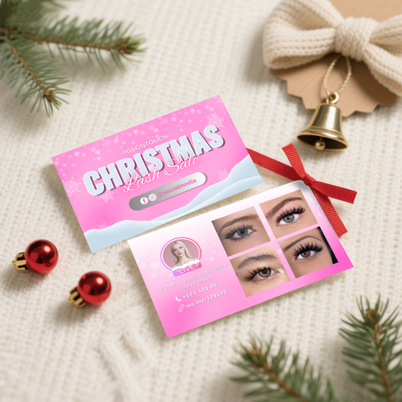 A stack of DSGNTOUCH blush and silver Christmas business cards displayed at a lash salon reception counter for clients to take