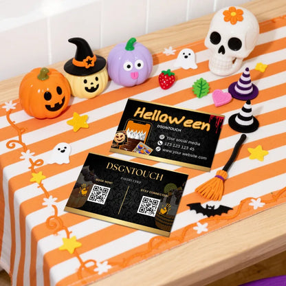 Halloween Cake Business Cards for Bakeries - 300GSM Gloss Laminated - DSGNTOUCH displayed on a festive Halloween table.