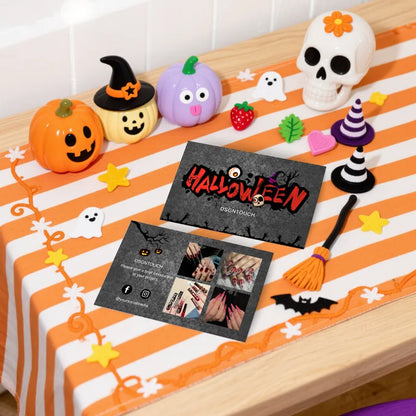 Halloween business cards displayed on a festive table with Halloween decorations at a nail salon.